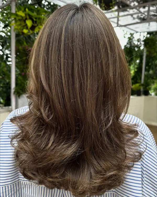 Sometimes all you need is a color refresh. Here, I blended in new highlights to brighten up her look and gave her a fresh cut with bouncy layers.
