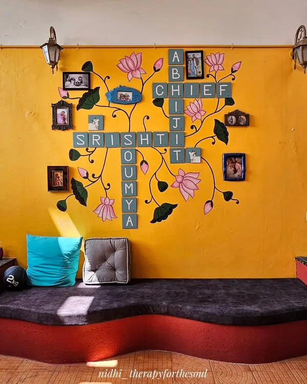 The finished Scrabble and Pichwai wall art in its home. The design combines the family's names with flowing lotus vines and integrates their photo frames, creating a truly personal art installation.