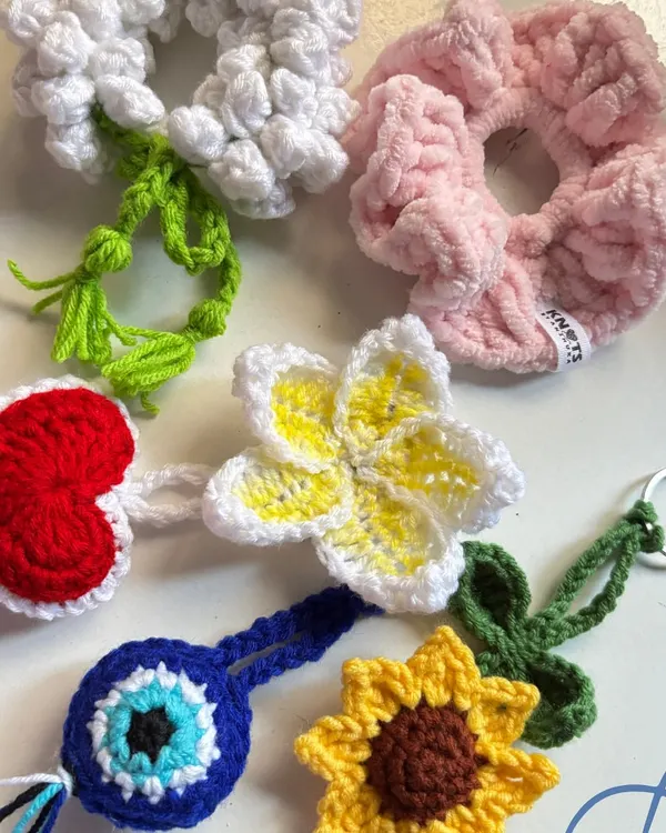 A flat lay of some of the small crochet items I made this week, including scrunchies, keychains, and charms.