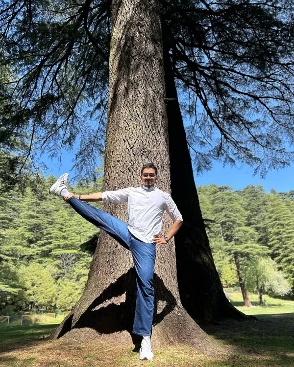 Practicing Utthita Hasta Padangusthasana (Extended Hand-to-Big-Toe Pose) next to a magnificent Deodar tree in Khajjiar, the mini Switzerland of India.