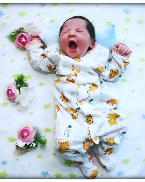 That perfect, tiny yawn. These are the fleeting moments I love to capture, freezing a memory that feels like it happened just yesterday. This little one is resting peacefully on a star-and-animal-themed blanket, ready for their first professional portrait.