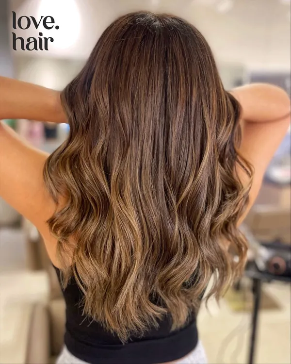 This is our signature serotonin boost in a hair colour. A beautiful brown balayage with honey tones that create warmth and dimension, styled into soft, flowing waves.