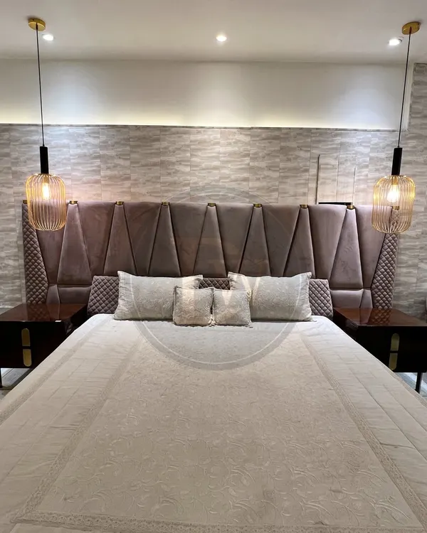 This bed makes a grand statement with its extra-tall, geometrically panelled headboard. Paired with dark wood side tables and modern pendant lights, it creates a dramatic and luxurious focal point.