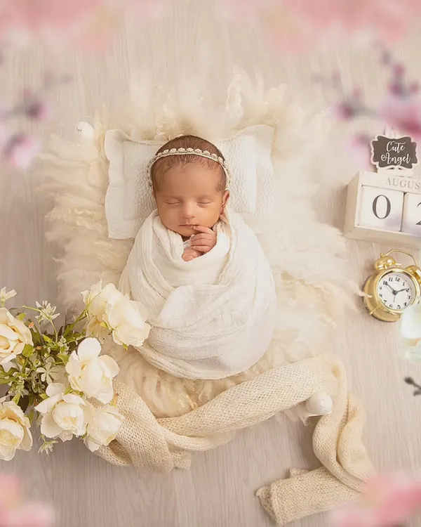 A classic and angelic setup. The baby is swaddled in white and rests on a soft, fluffy surface with a tiny pillow, creating a pure and serene portrait.
