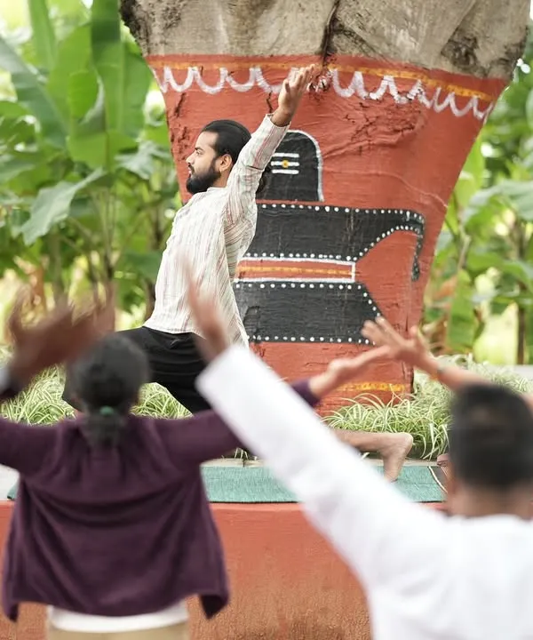 Leading a morning yoga session outdoors. This posture, a variation of a lunge, opens up the chest and shoulders, countering the effects of hunching over a desk. The participants mirror the movement, creating a sense of unity.