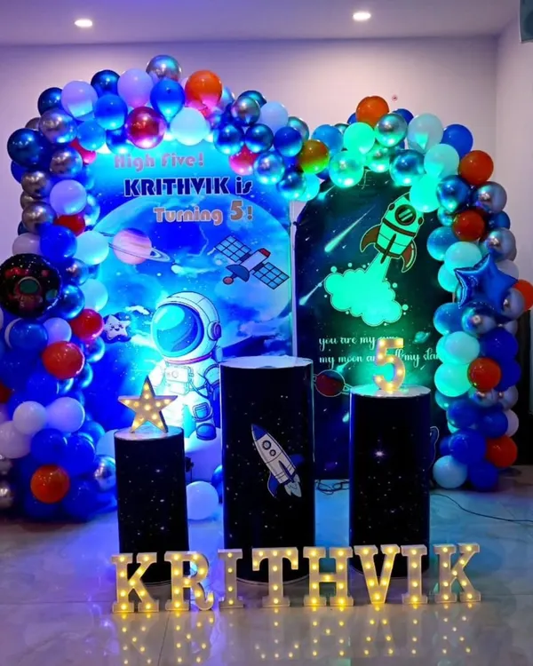 This outer space theme is one of my most requested setups for kids' birthdays. It features a custom printed backdrop, a multi-colored balloon arch, illuminated marquee letters for the name, and themed pedestals for the cake.