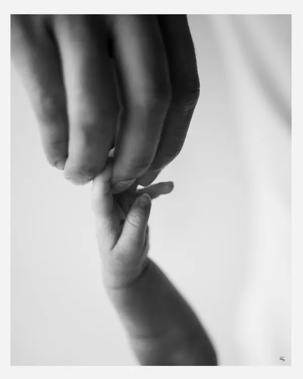 The tiniest grasp. This macro shot of a newborn's hand holding a parent's finger is a powerful, minimalist portrait of trust and connection, made timeless in black and white.