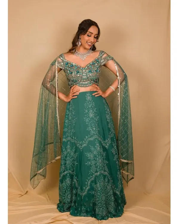 This teal green lehenga is a beautiful option for a reception or sangeet. It features delicate silver embroidery and modern cape-style sleeves for a touch of drama.