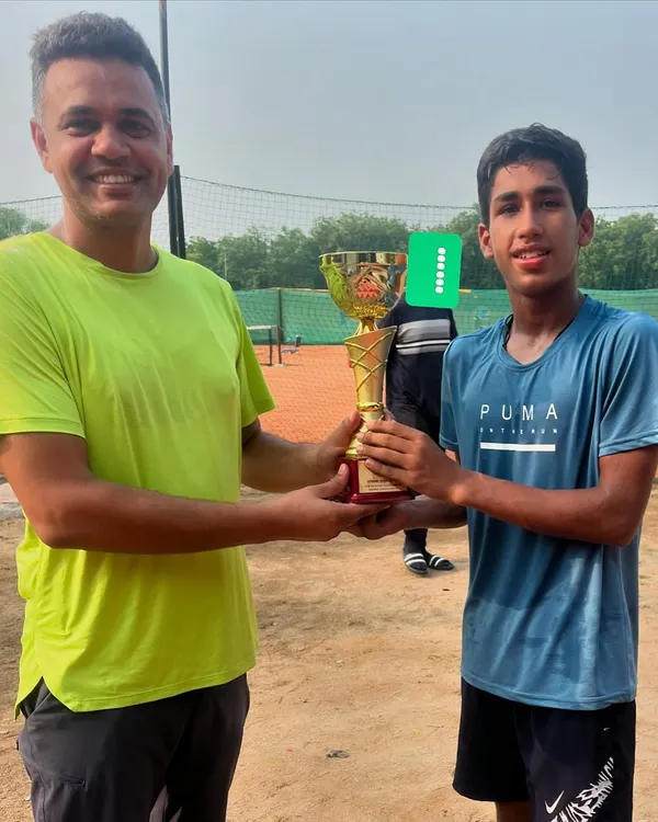 Harsh Nandal, winner of the U16 boys' title at a UTR tournament, receives his trophy from a coach. His smile reflects the hard work that goes into preparing for and winning these events.