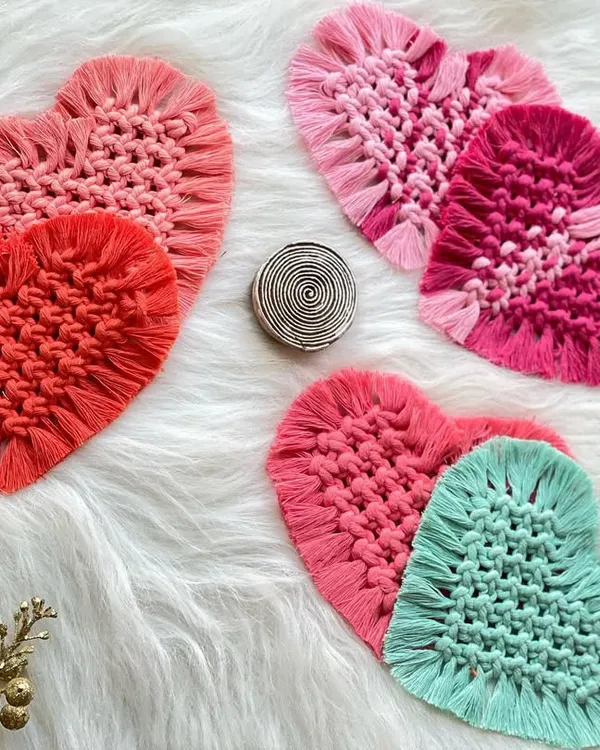 A collection of my heart-shaped macrame coasters in various shades of pink, red, and teal. They are perfect for adding a pop of color and love to your coffee table.