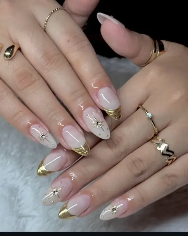 An elegant take on the French manicure, featuring almond-shaped extensions with a metallic gold tip. Each nail is accented with a delicate starburst rhinestone for a touch of luxury.