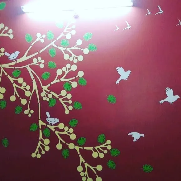 This vibrant red accent wall is brought to life with a nature-themed stencil. The design features a stylized tree, leaves, and birds, creating a cheerful and dynamic atmosphere in the room.