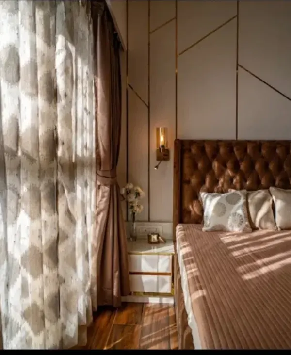 Waking up here feels like a dream. The morning light filters through the sheer curtains, highlighting the geometric wall paneling and the plush, tufted headboard that serves as the room's centerpiece.