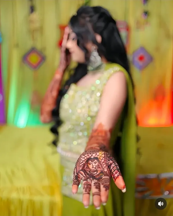A close-up of a bride's portrait drawn on the palm, complete with a veil (ghunghat) and jewelry. This is a popular choice for brides who want a truly personal touch in their mehandi.