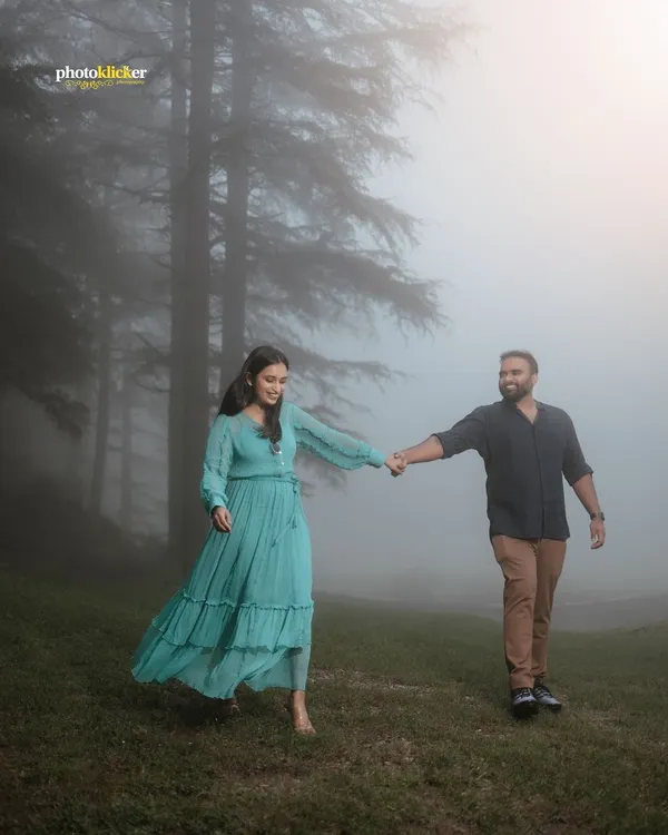 A couple walks hand-in-hand through a misty forest, creating a dreamy and romantic atmosphere for their anniversary photoshoot in the mountains.