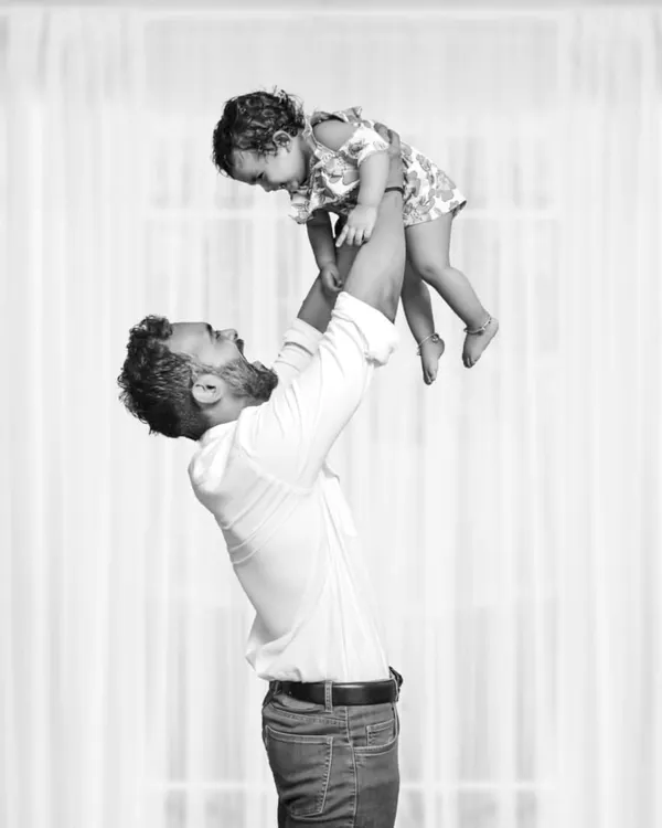 A powerful black and white shot of a father joyfully lifting his daughter into the air, capturing a moment of pure happiness and the special father-daughter bond.