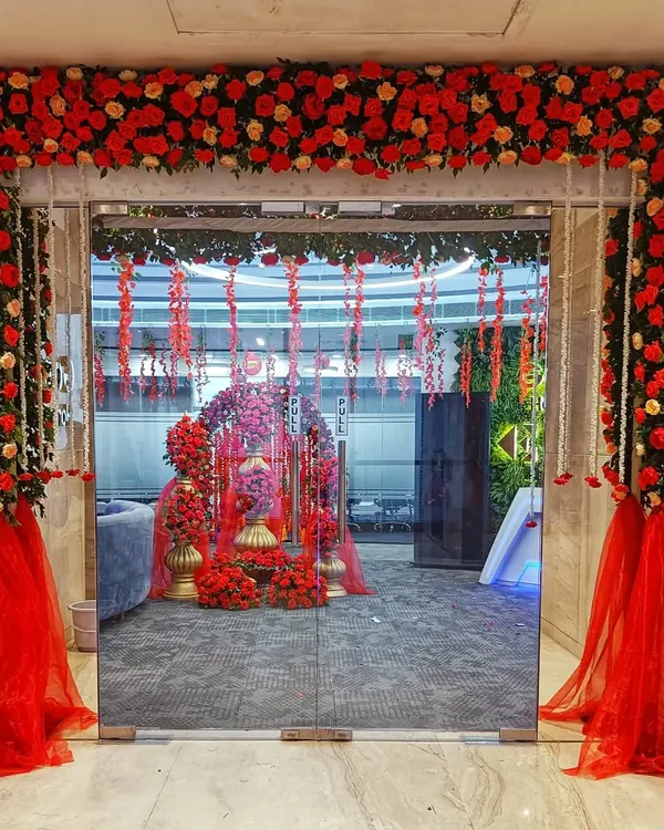 A grand entrance sets the stage for a memorable event. This doorway, framed with an abundance of red and peach roses and accented with sheer red fabric, created a dramatic and romantic entryway for a special office celebration.
