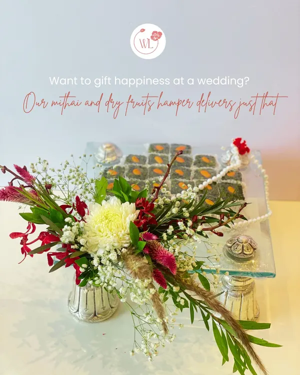This is my classic mithai and dry fruits hamper, designed to deliver happiness. Here, I've arranged gourmet pistachio sweets on a clear glass tray, accented with a fresh floral bouquet and traditional elements.