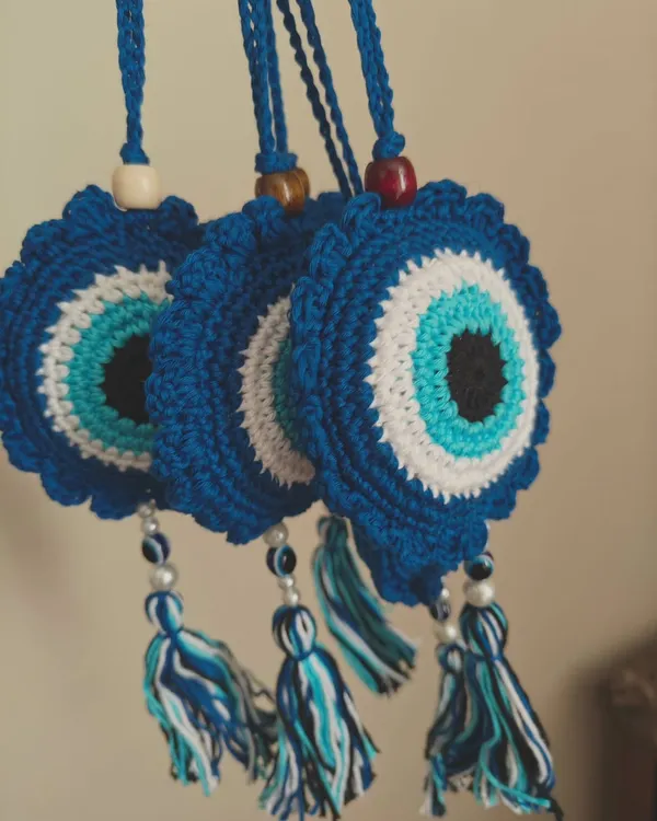 A set of my crochet Evil Eye car charms, ready to protect against bad vibes. Each one is made with deep blue, white, and turquoise yarn and finished with a tassel.