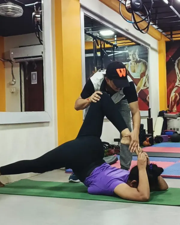 In personal training, I provide hands-on assistance to help you find the correct alignment in challenging poses, like this supine leg stretch, ensuring you get the maximum benefit safely.