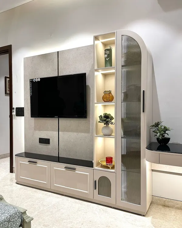 A closer view of our multi-functional TV unit. The design includes a tall cabinet with fluted glass for display, drawers for storage, and an attached, backlit study table, all in one cohesive piece.