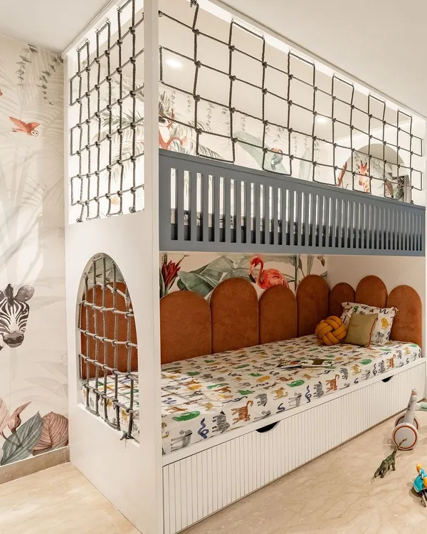 This custom bunk bed is the star of the room, with a sleeping area below and a netted play area on top. The jungle-themed wallpaper and animal-print bedding create a fun, immersive environment for a growing boy.