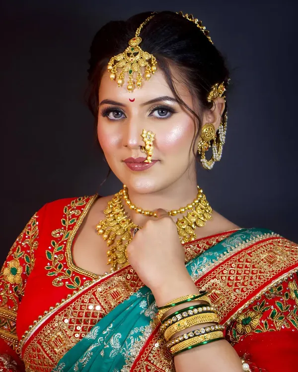 The quintessential Maharashtrian bride, complete with a traditional nath and layered gold jewellery. This look combines classic elements to create a timeless and elegant style.
