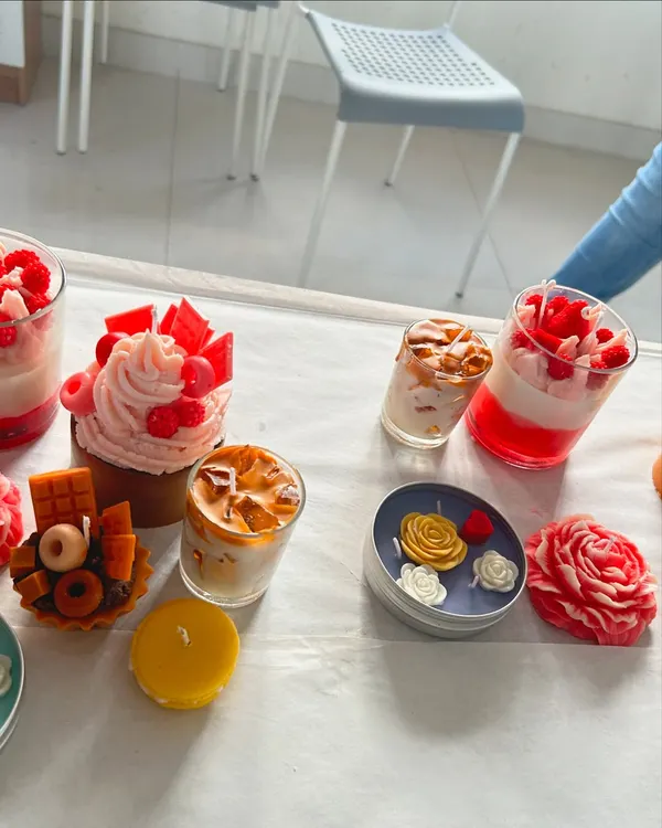 A beautiful spread of finished dessert and floral candles from one of our workshops. You can learn to make a variety of styles, including cupcake candles, macaron candles, and layered jar candles.