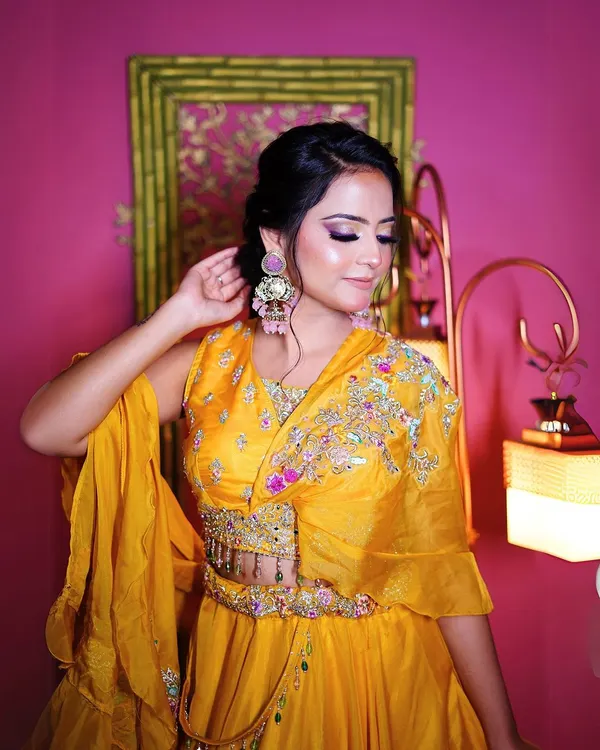 This vibrant yellow lehenga with a modern cape-style blouse is perfect for a Haldi ceremony look. The colorful embroidery adds a festive touch.