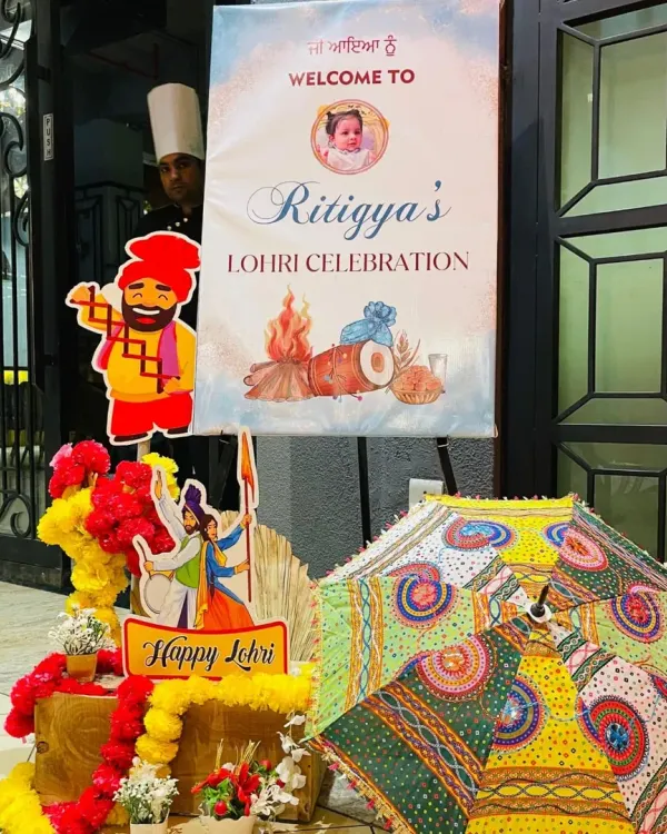 The welcome sign I created for Ritgya's first Lohri celebration. The personalized standee features bonfire graphics and is surrounded by colorful Punjabi-themed props.