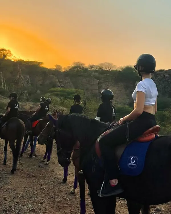 A group of riders pauses on a trail to watch the sunset over the Aravalli hills. This is a signature moment from our horseback safari, offering a peaceful and picturesque end to an adventurous day.