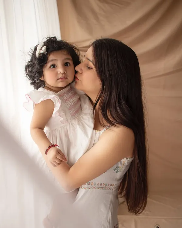 A mother's gentle kiss. This close-up, candid moment is so full of love and tenderness, captured in our soft and neutral boho setting.