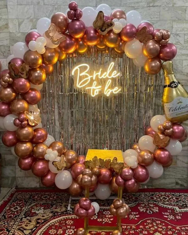 A popular choice for bridal showers, this circular frame is covered in rose gold and white balloons. The design is elevated with a "Bride to be" neon sign and a large champagne bottle foil balloon for a fun, celebratory touch.