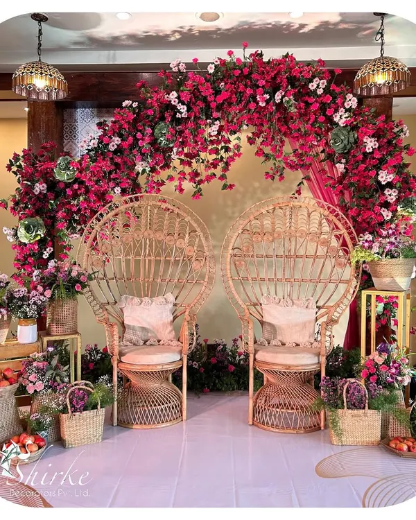 A unique and bohemian-inspired seating area for a Mehendi or Haldi. We used peacock-style wicker chairs and a stunning backdrop of fuchsia bougainvillea to create a vibrant and stylish photo corner.