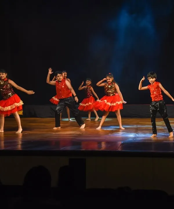 Our young performers light up the stage in vibrant red costumes for a Bollywood group dance. This image captures the energy and coordination we teach in our kids' classes.