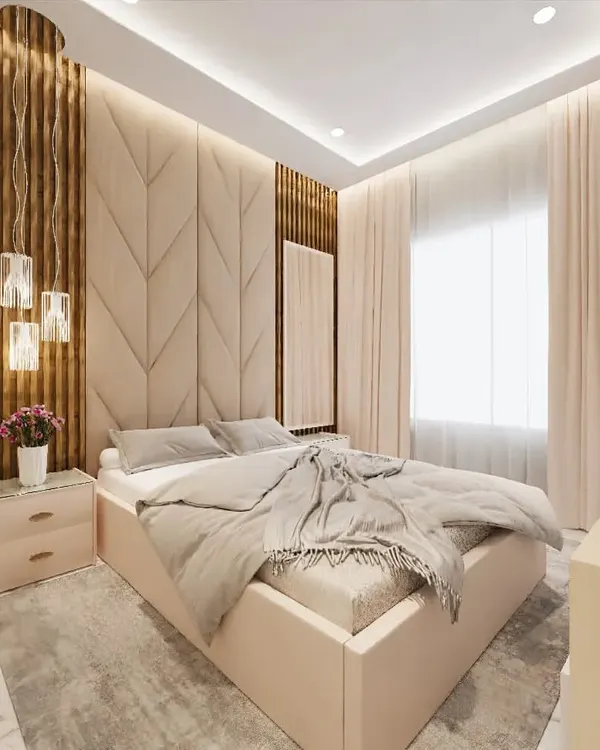 This cozy bedroom design uses a combination of a chevron-patterned upholstered headboard and vertical wooden fluting. The warm pendant lights add to the relaxing ambiance, creating a perfect space to unwind.