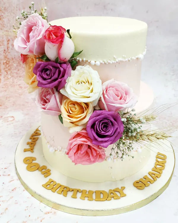 This two-tiered floral fault line cake is the epitome of modern elegance. A cascade of fresh roses in shades of pink, purple, and cream appears to burst through the delicate pink and ivory tiers, creating a design that is both dramatic and romantic, perfect for a milestone birthday or engagement party.