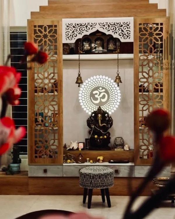 A beautifully framed shot of a completed pooja unit, showcasing the intricate jali work doors, backlit 'Om' symbol, and the serene atmosphere it creates.