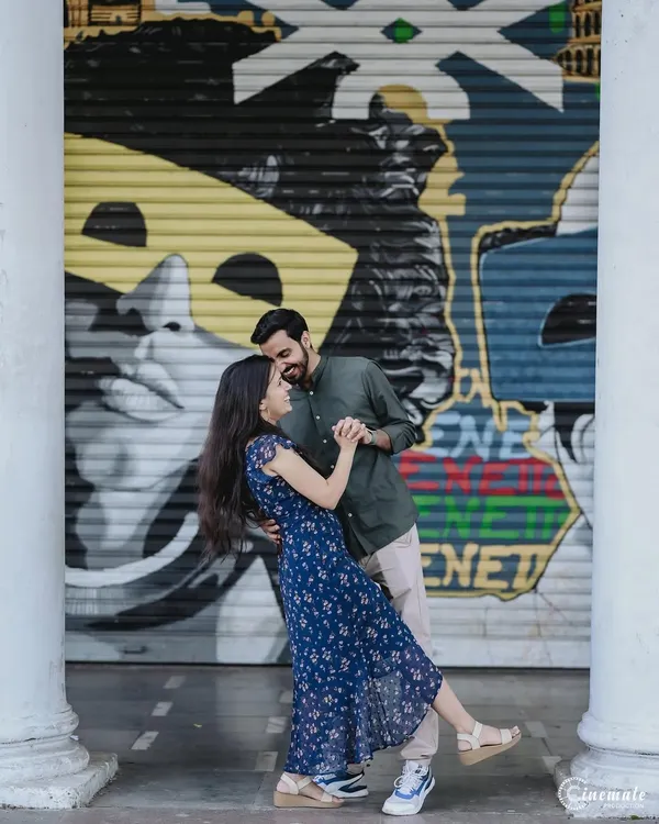A dynamic shot of a couple dancing in Connaught Place, Delhi. The vibrant street art provides a cool, modern backdrop that perfectly matches their energetic and fun-loving personalities.