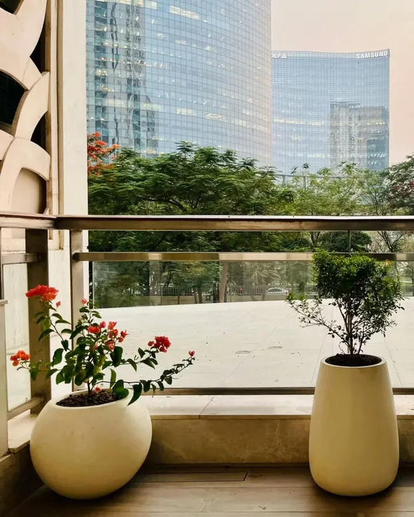 A serene balcony we designed for Mr. Lokvir Kapoor, Co-founder of Pine Labs, at DLF Camellias. The minimalist design features elegant planters against the stunning backdrop of the city skyline, creating a peaceful urban escape.