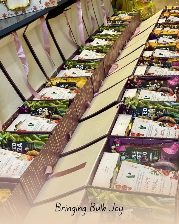 This image shows a lineup of Diwali hampers ready for a corporate client. Each box is consistently packed with a selection of healthy snacks and a personalized "Happy Diwali" card, ready for distribution.