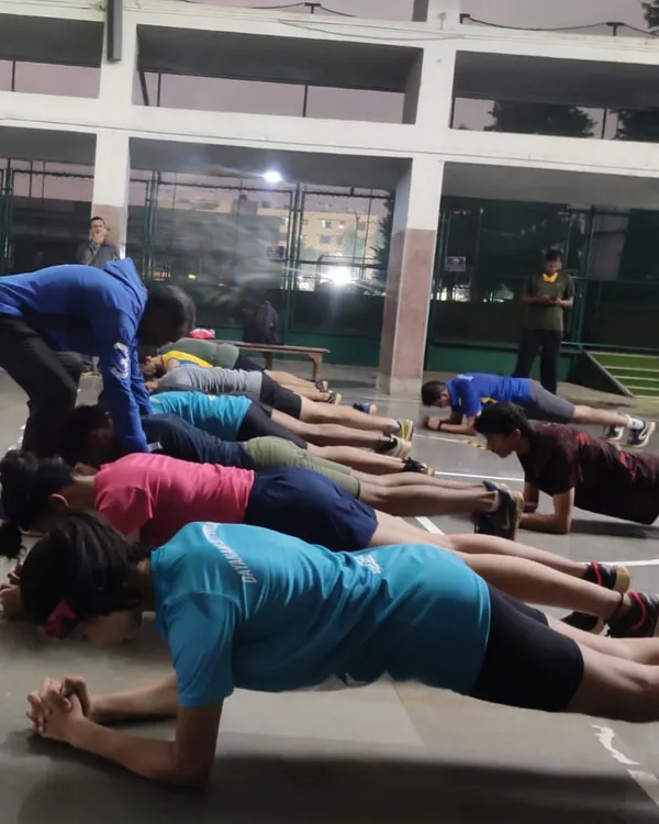 A coach provides individual correction during a group planking session. We emphasize perfect posture to maximize core engagement and protect the spine, a fundamental principle in our injury prevention training for track and field athletes.