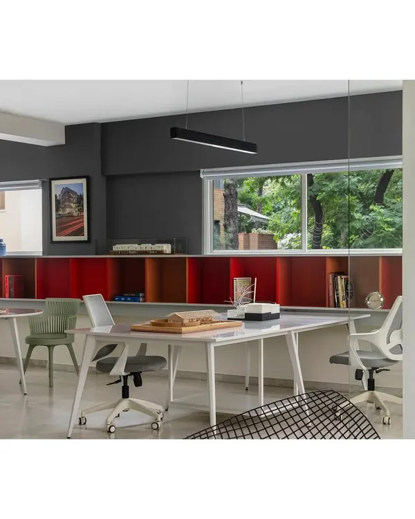 Our Pune studio, located in the leafy neighborhood of Koregaon Park. The workspace is organized around a long shelving unit in red, yellow, and blue, which houses our library of architectural books and models, reflecting our vibrant and intellectual design approach.