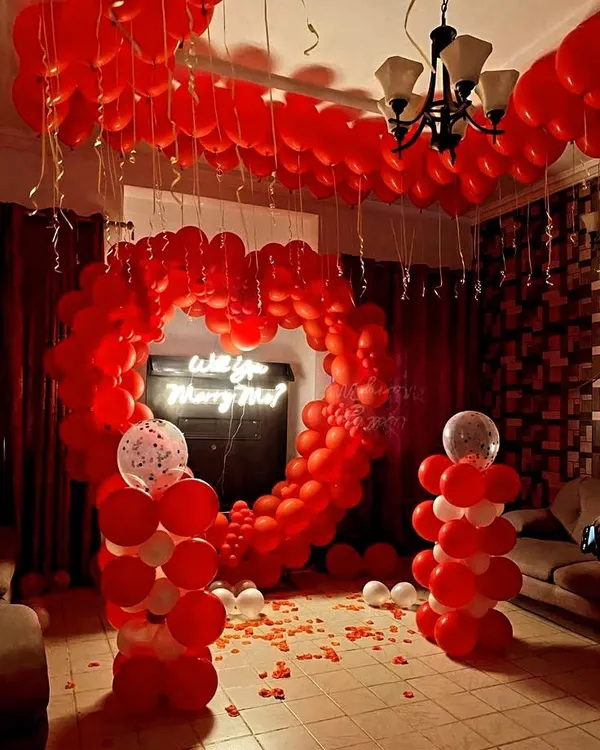 A full view of a romantic proposal decoration I arranged in a client's living room. The design centers around a heart-shaped balloon arch and a glowing 'Will you Marry Me?' neon sign, creating a magical pathway for the big question.