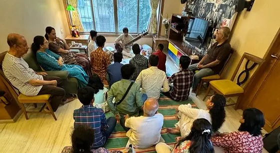 A classic 'baithak' at a private residence. The audience is seated close, creating a cozy and informal atmosphere where they can truly connect with the music.