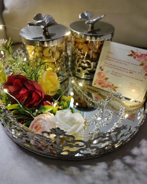 This is the kind of first impression I love to create. This wedding invitation hamper features an ornate silver tray, decorative jars filled with premium nuts, and a personalized note, all illuminated by delicate fairy lights to create a magical unboxing experience.