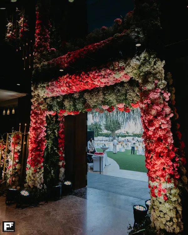 A grand entrance is the first chapter of your wedding story. We created this magnificent, dense floral archway in shades of red and pink to give guests a breathtaking glimpse of the celebration waiting inside.