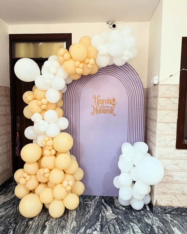 The complete 'Umrah Mubarak' decoration setup. The asymmetrical balloon arch and custom backdrop create an elegant and welcoming entrance for guests.