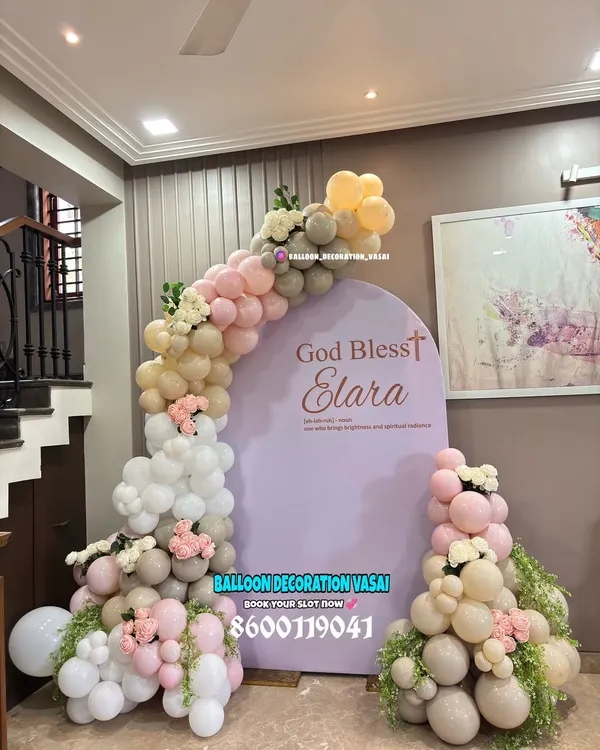 An elegant and modern naming ceremony backdrop with the message "God Bless Elara". The soft, muted tones of the balloons and the clean arched backdrop create a sophisticated and heartfelt setting.