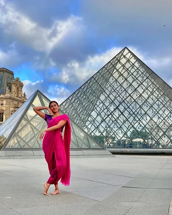 Striking a dance pose in a saree in front of the iconic Louvre Pyramid in Paris. This image is a beautiful fusion of Indian tradition and world-famous architecture.